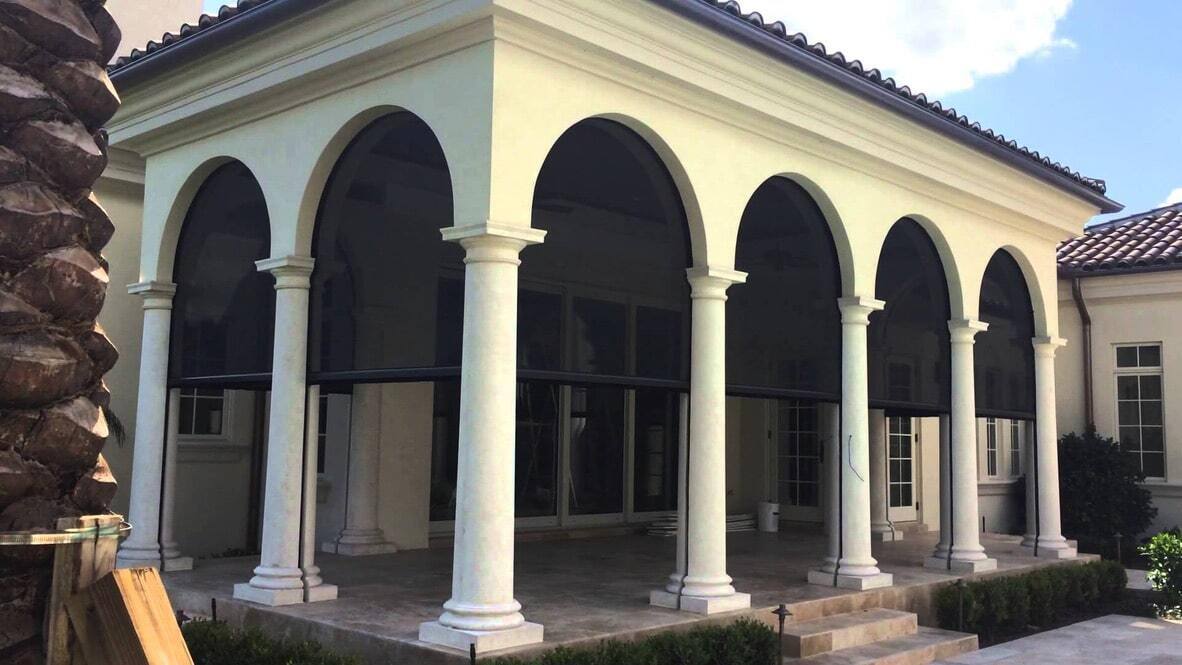 Dark exterior screens fitted within a series of tall arched patio openings.