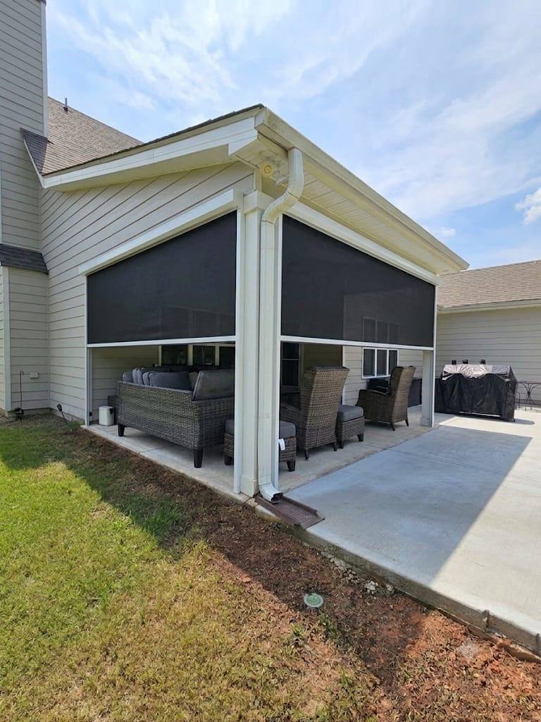 Partially lowered dark screens with white frames around a furnished corner patio.