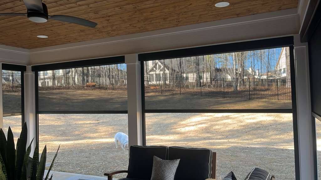 Garden and woodland views through partially lowered screens beneath a wood patio ceiling.
