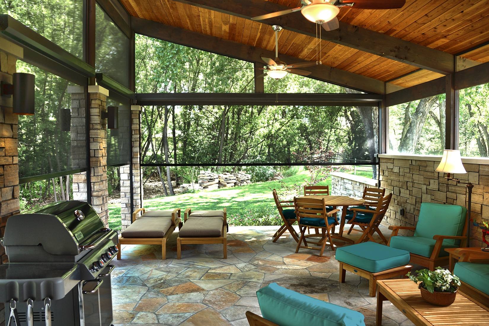 Covered outdoor living space with solar screens, a timber ceiling, stone columns, and garden views.